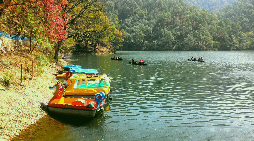 Sattal lake — red autumn leaves over still green water with wooden boats